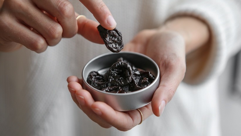 A person holding a bowl of prunes

Description automatically generated